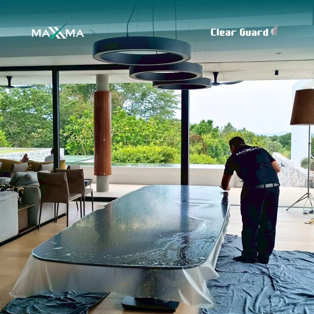 ช่างผู้เชี่ยวชาญกำลังติดตั้งฟิล์มใสกันรอย Clear Guard ลงบนโต๊ะอาหารขนาดใหญ่
